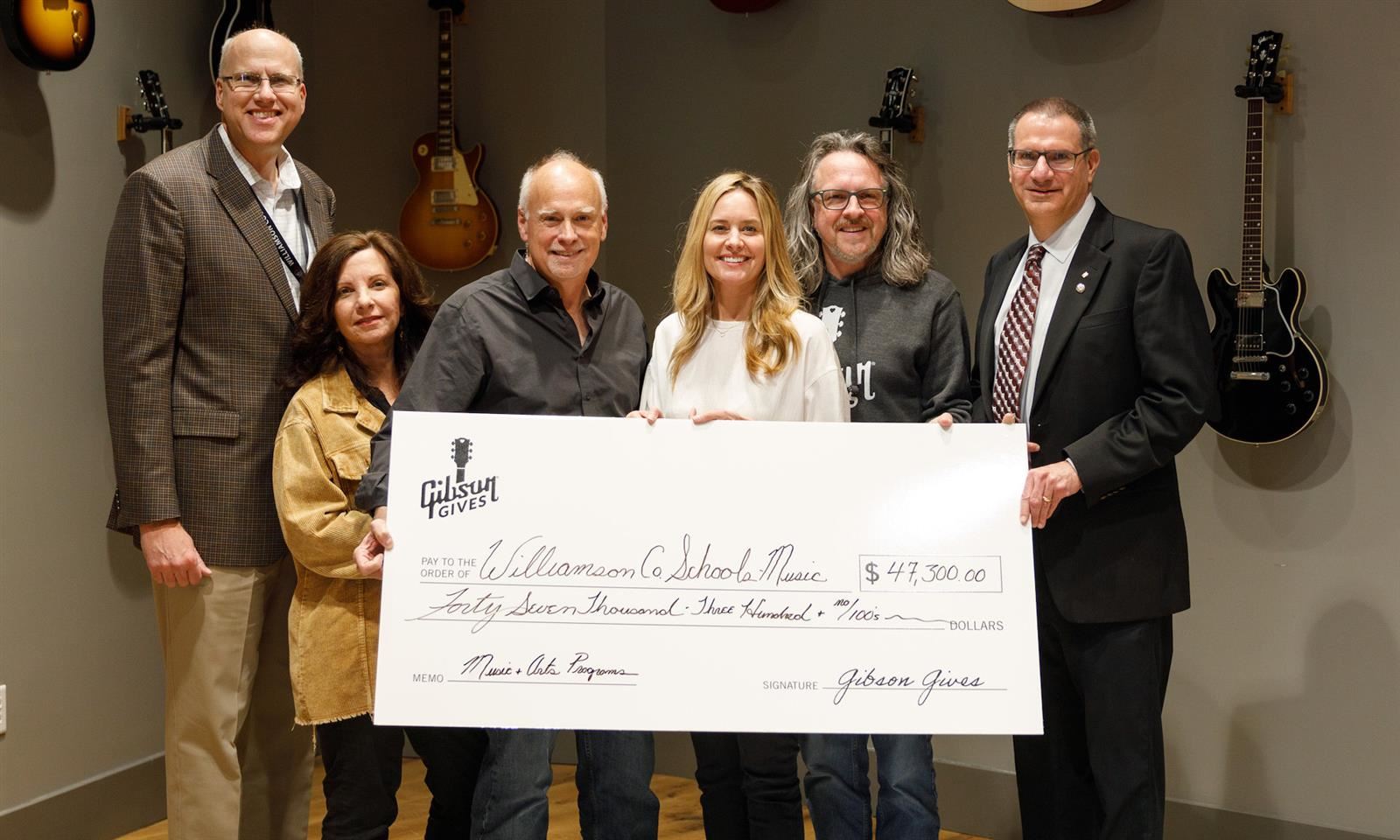 Administrators and leaders hold a large check